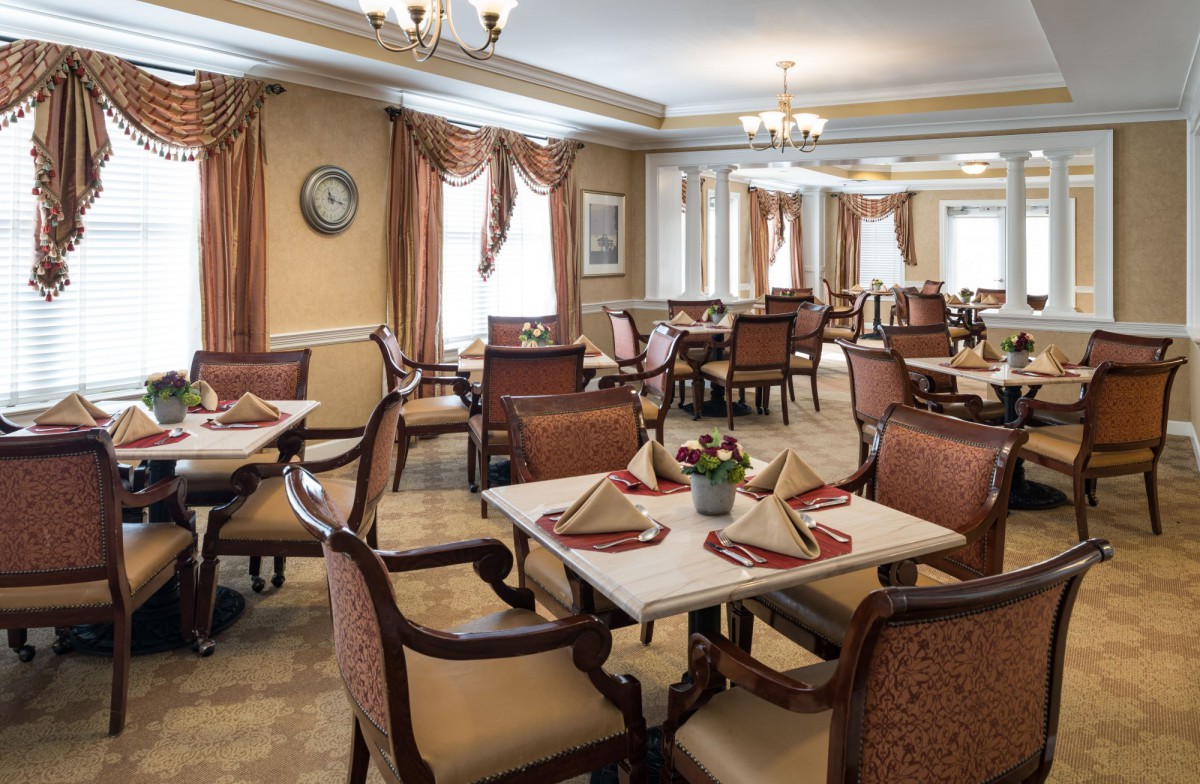 An elegant dining room with neatly arranged tables and chairs, featuring classic decor and place settings.