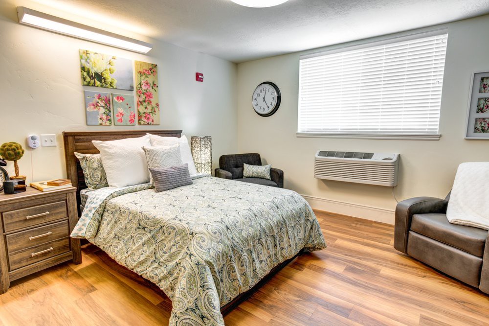 A cozy and modern bedroom interior with a neatly made bed, decorative paintings, and a large wall clock.
