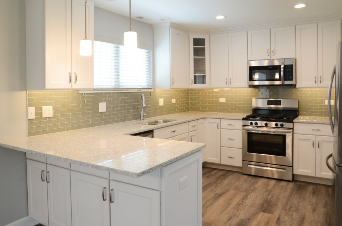 A modern kitchen with white cabinets and stainless steel appliances.