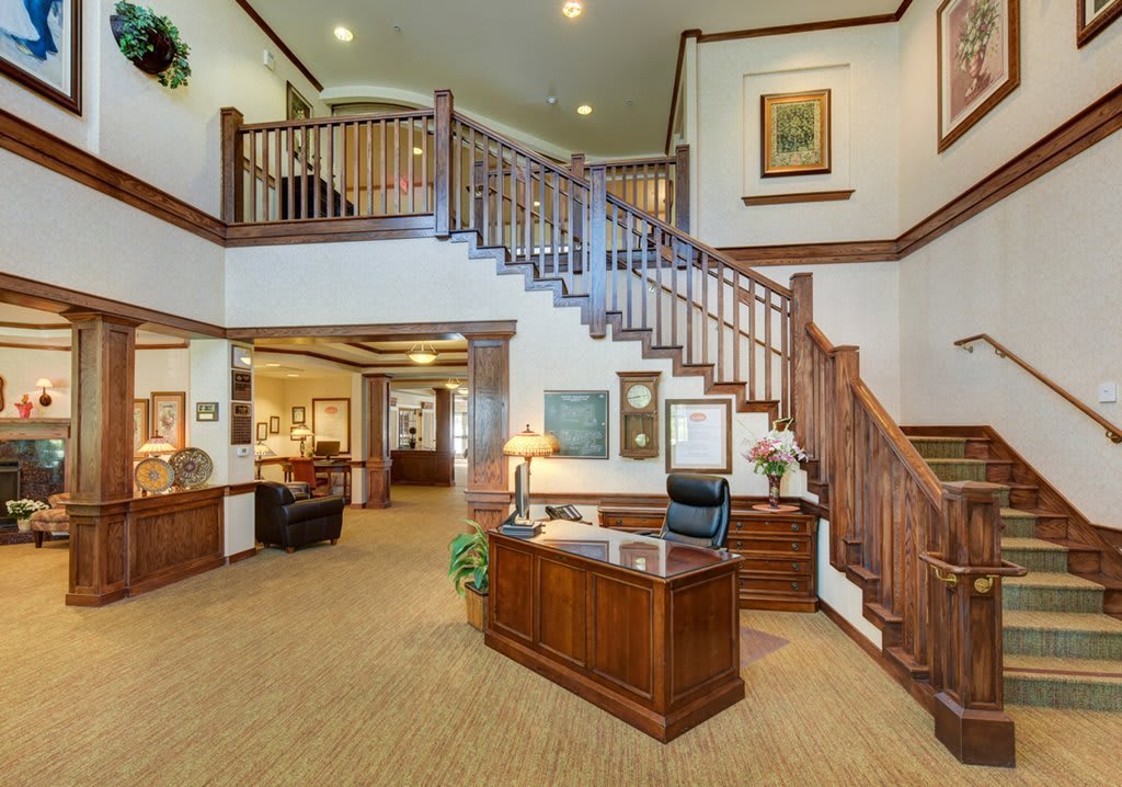 A spacious office reception area with a wooden staircase and desk.
