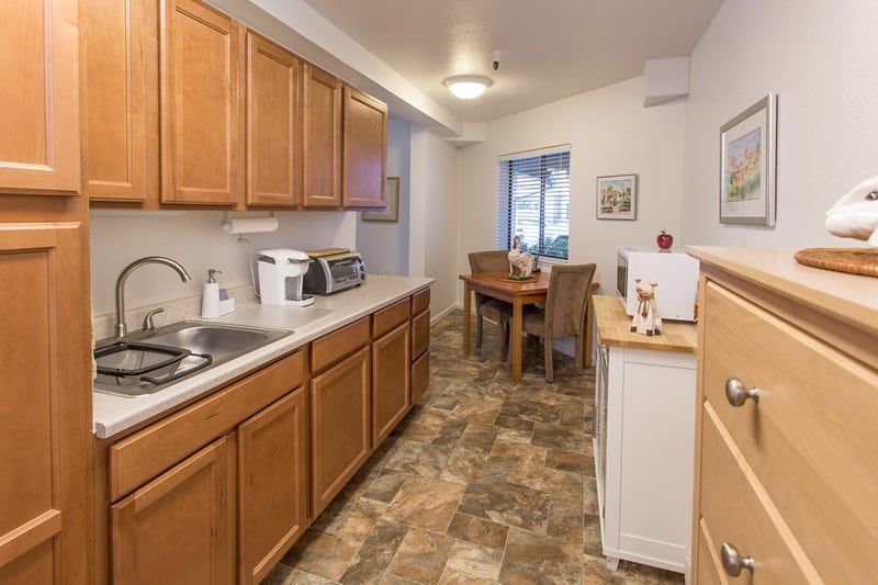 A cozy kitchen and dining area featuring wooden cabinets, a small dining table with chairs, and various kitchen appliances.