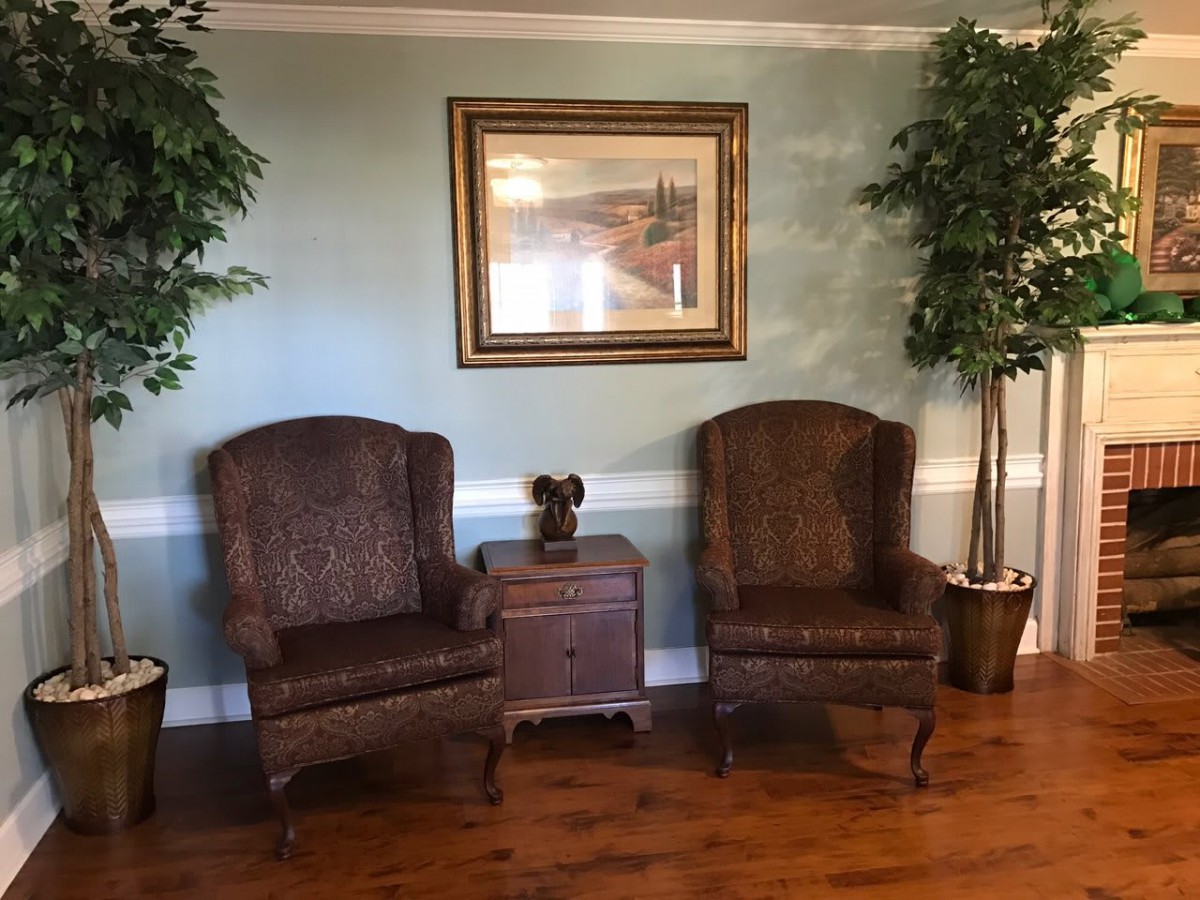 A cozy seating area with two armchairs, a side table, and decorative indoor plants.