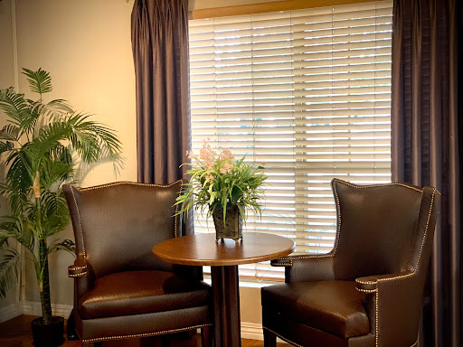 A cozy seating area featuring two chairs, a small table, and a vase of flowers by the window.