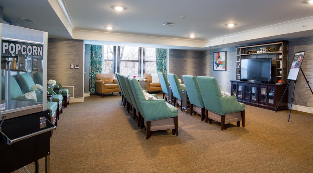 A cozy home theater room with rows of comfortable armchairs facing a large screen.