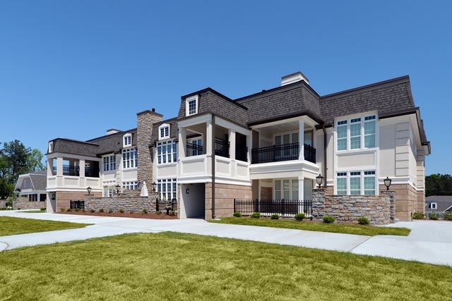 A modern luxury residential building with manicured lawns and a classic architectural style.