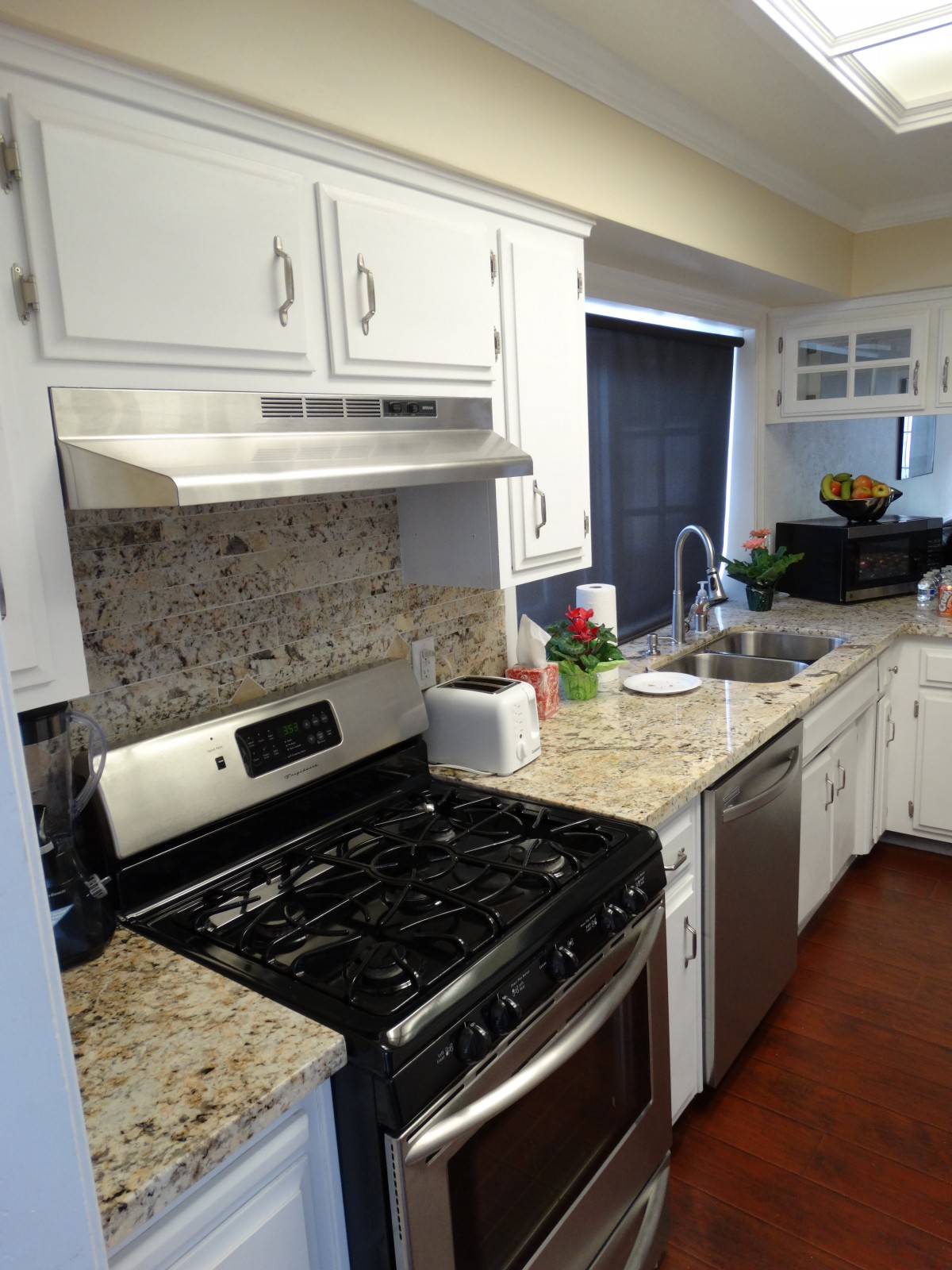 A modern kitchen with a gas stove, white cabinets, and granite countertops.