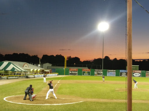 A thrilling baseball game under the evening sky as the sun sets.