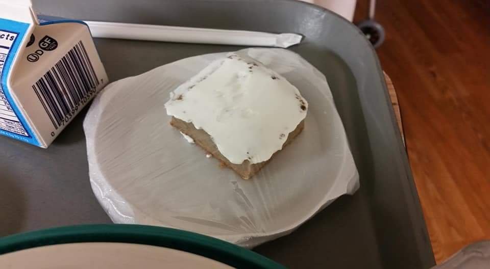 A piece of cake with white frosting served on a tray.