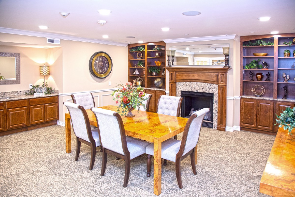 A well-appointed dining room featuring a wooden table and upholstered chairs, with decorative elements such as a fireplace and bookshelves.