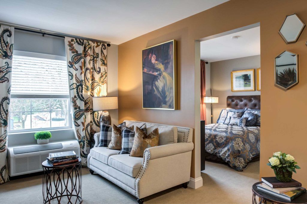 A cozy living room adjoining a bedroom, featuring elegant decor and warm tones.