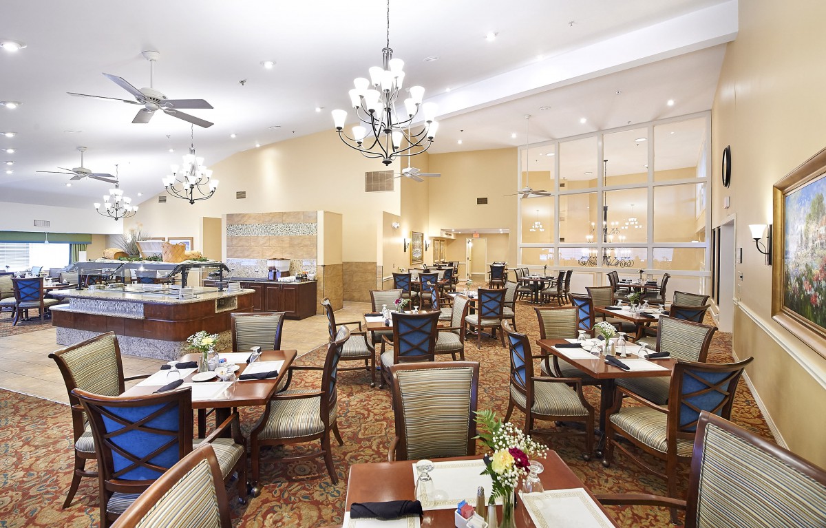 A spacious and elegantly decorated restaurant dining area with neatly arranged tables and chairs under chandeliers.