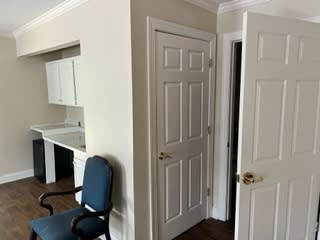 Interior view of a hallway with doors and a blue chair.