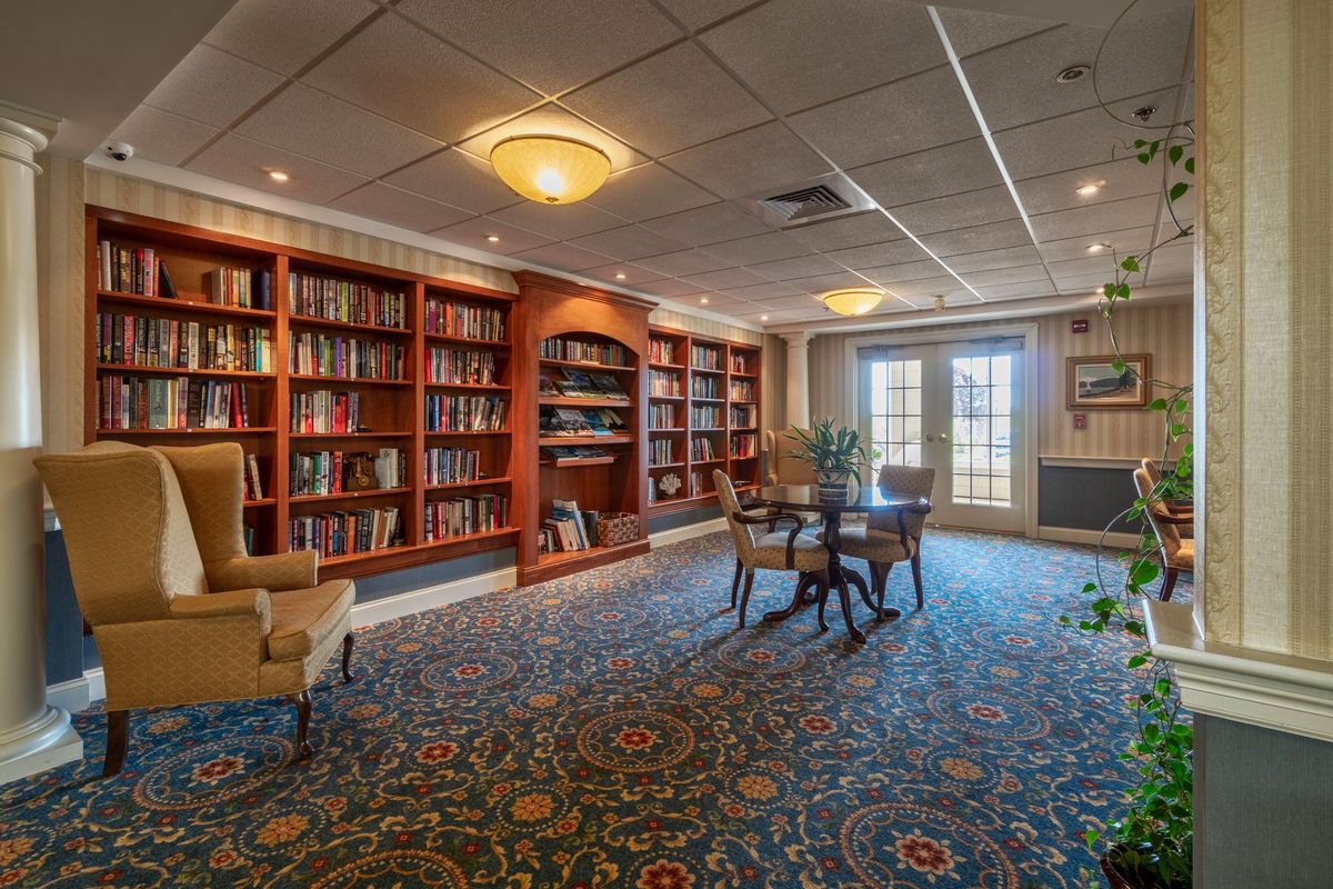 A cozy library with wooden bookshelves and comfortable seating.