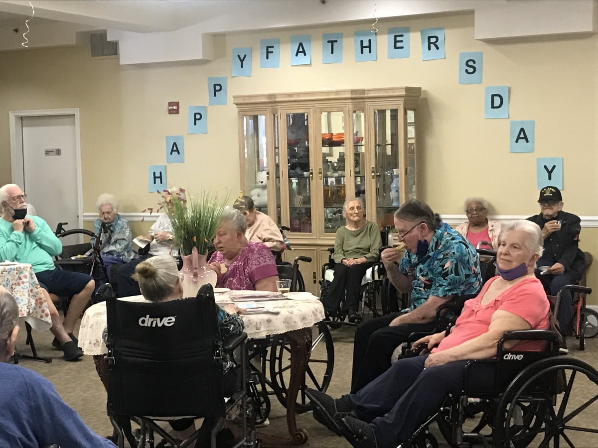 Elderly residents gather for a Father's Day celebration in a nursing home.