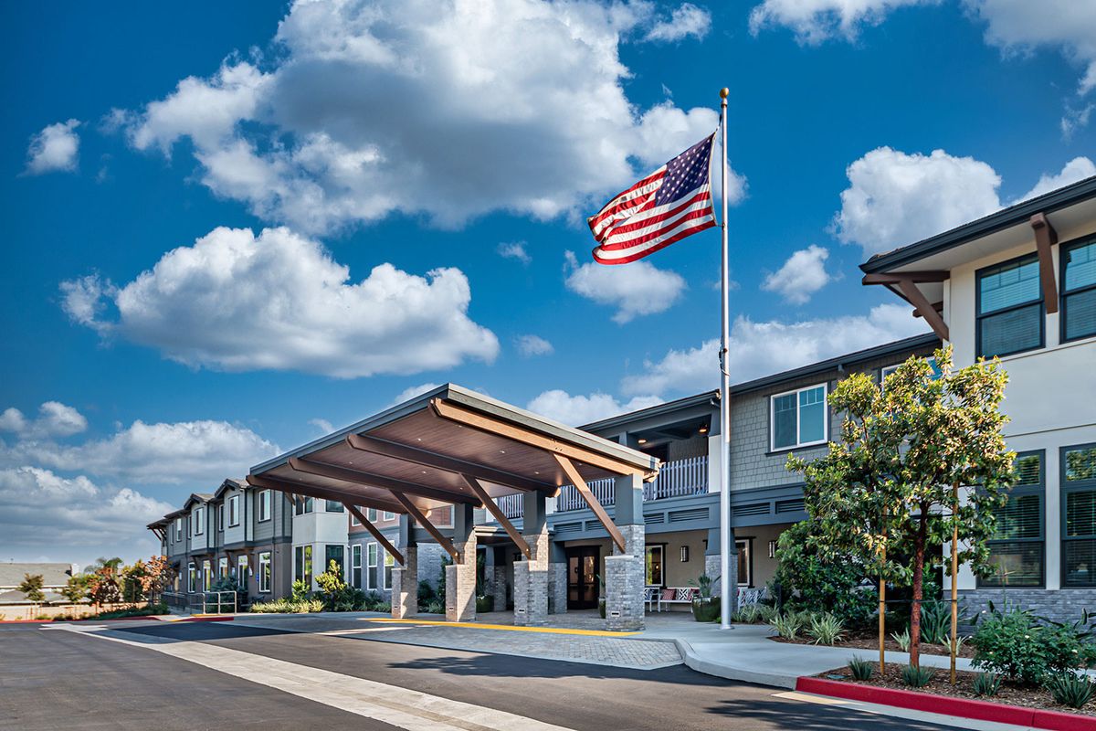 A modern building with an American flag flying under a partly cloudy sky.