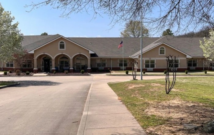 A suburban residential building with a driveway and trees.