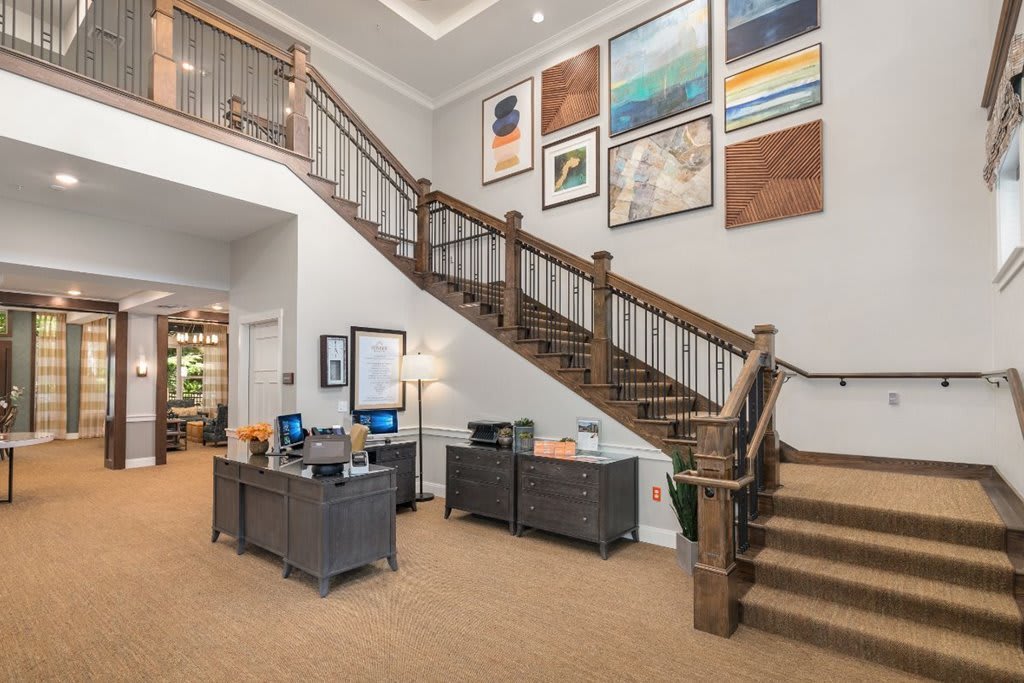 A spacious office lobby featuring a decorative staircase and modern artwork on the walls.