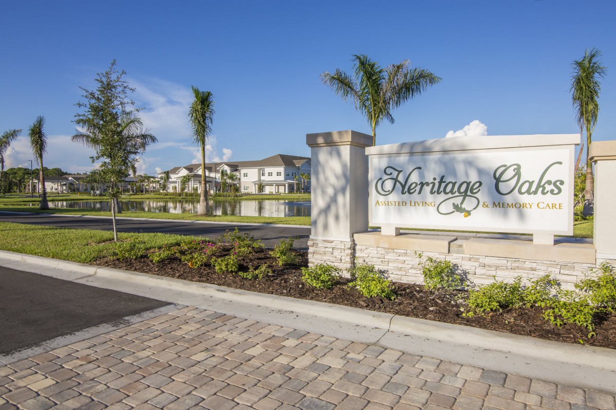 Entrance sign to a residential community with palm trees and well-maintained landscaping.