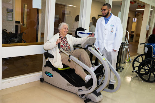 An elderly patient engages with exercise equipment under the supervision of a medical professional, highlighting the importance of rehabilitation in healthcare settings.