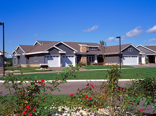 A charming suburban home with a well-manicured lawn and blooming flowers under a clear blue sky.