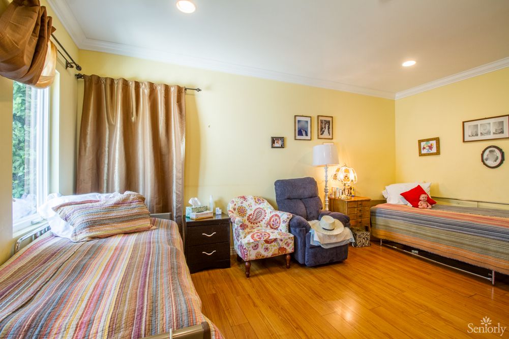 A cozy bedroom with two beds, a recliner chair, and warm lighting.