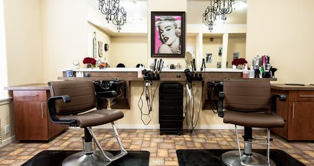A stylish hair salon interior featuring chairs, mirrors, and chic lighting.