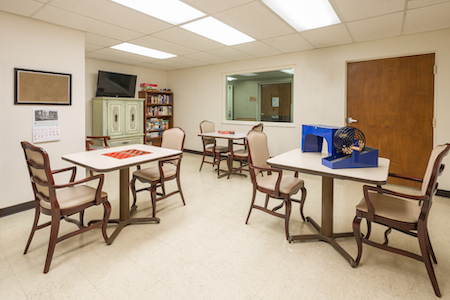 A well-lit room featuring tables and chairs, designed for meetings or group activities.