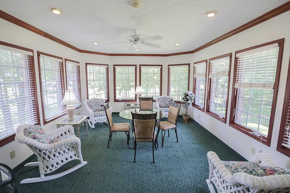 A bright sunroom with wicker furniture and large windows.