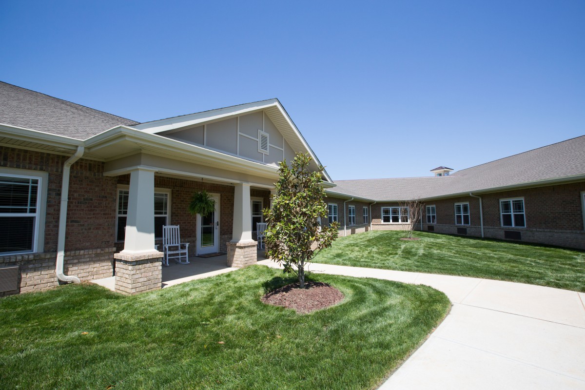 A well-maintained building with a lush lawn and a curved pathway under a clear blue sky.