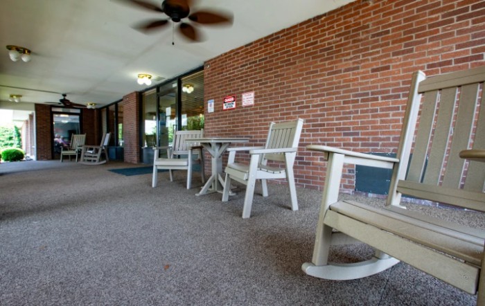 A cozy patio area with rocking chairs and a table against a brick wall.