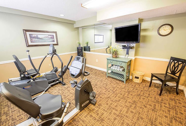 A small fitness room with exercise bikes, a television, and a mirror.