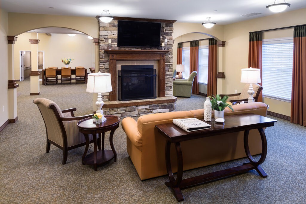 A cozy living room with a stone fireplace, comfortable seating, and a television mounted above.