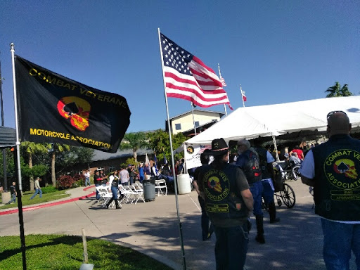 A gathering featuring an American flag and another flag, with attendees enjoying the outdoor event.