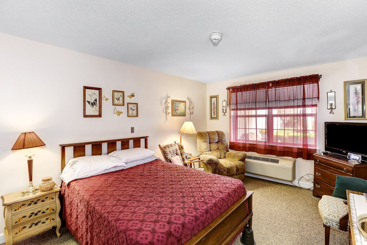 Cozy bedroom with a wooden bed, armchair, and decorative artwork.