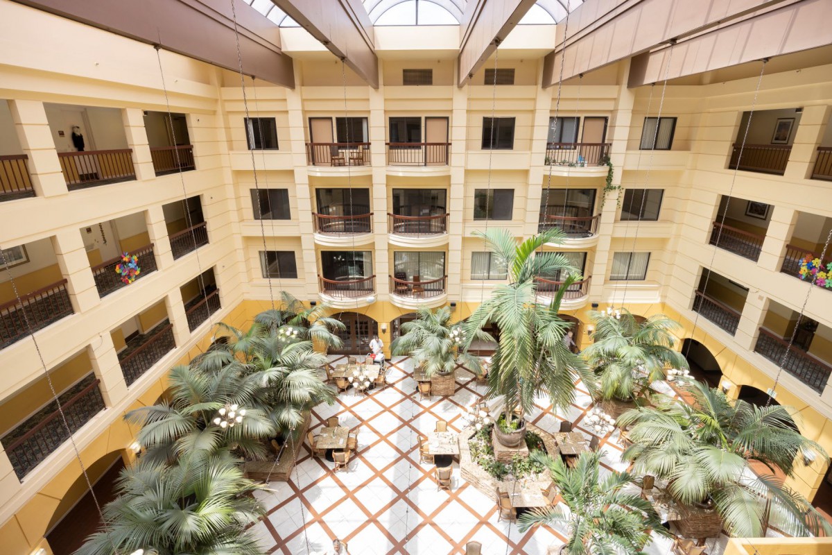 A spacious atrium with lush plants, surrounded by balconies and illuminated by a skylight.