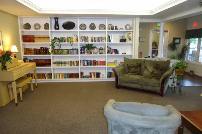 A cozy library space featuring bookshelves filled with books and decorative items, complemented by comfortable couches.
