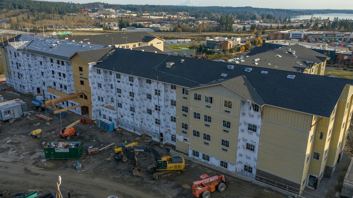 An apartment complex under construction with scaffolding and heavy machinery on site.