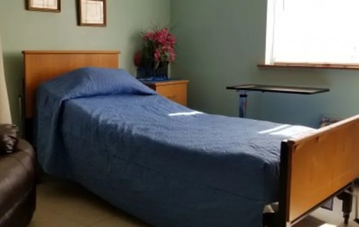 A simple bedroom with a single bed covered in blue bedding and minimal decor.