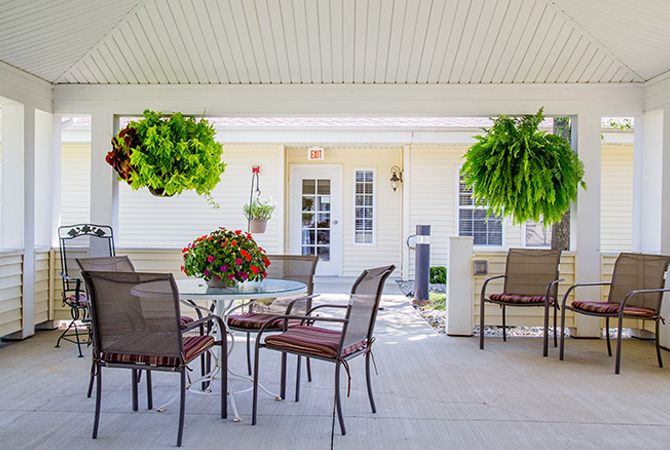 Cozy outdoor patio with seating and lush hanging plants.