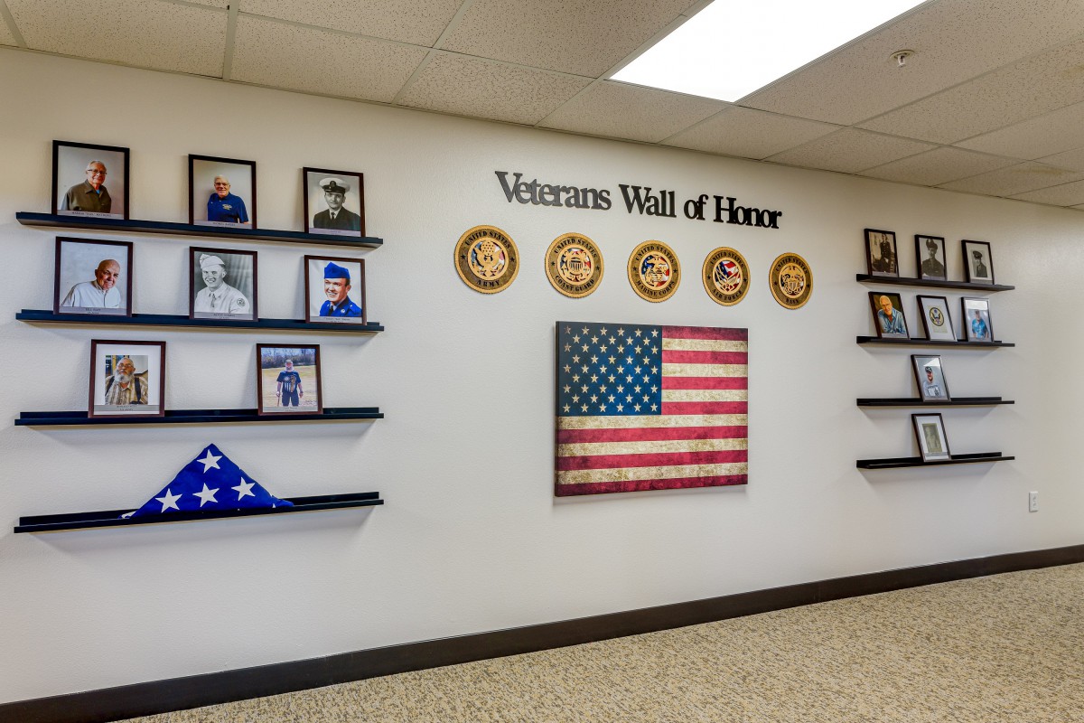 A Veterans Wall of Honor displaying photos and symbols of military service alongside the American flag.