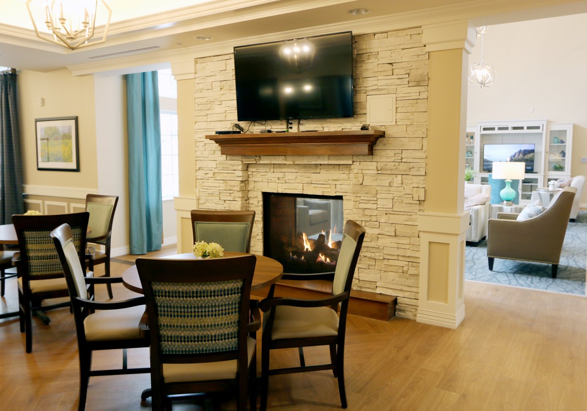 A cozy living room with a stone fireplace, mounted television, and a dining table with chairs.