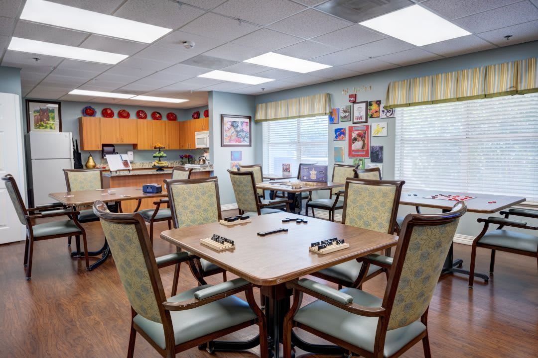 A well-lit dining area with neatly arranged tables and chairs, featuring large windows and various decorations on the walls.