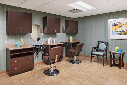A modern salon interior featuring stylish chairs, mirrors, and storage cabinets.