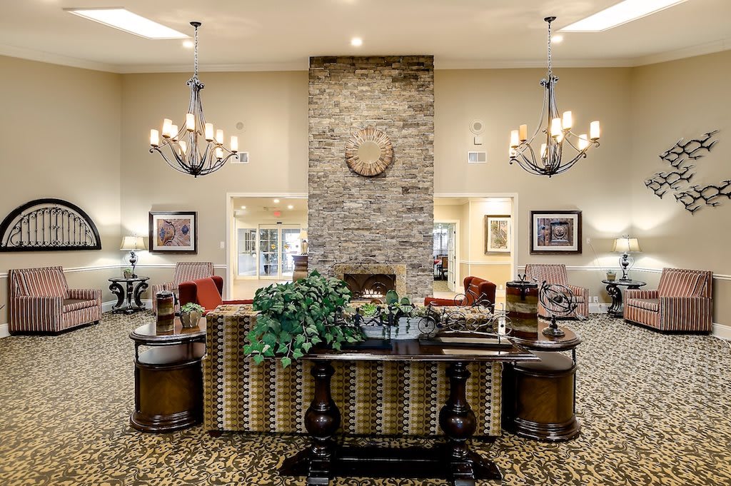 A cozy and elegant lobby featuring chandeliers, a brick fireplace, and a comfortable seating area.