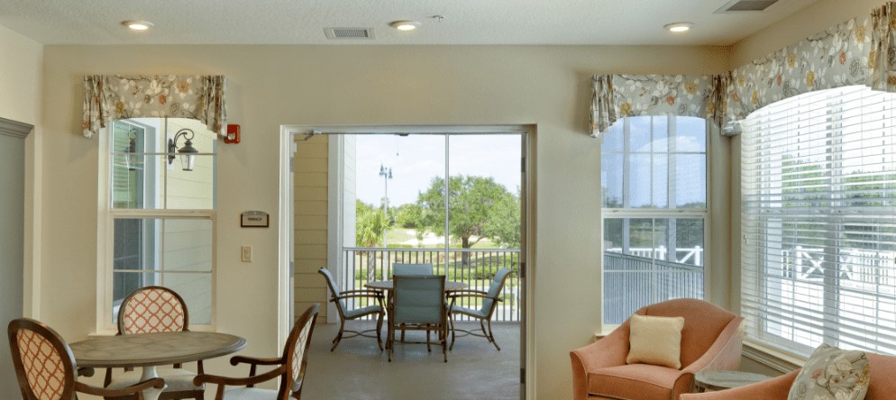A cozy living room with a view of the balcony featuring outdoor seating and greenery.