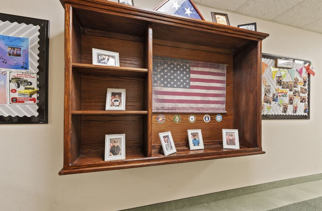 A wooden display case featuring an American flag, photographs, and military medals.