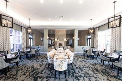 A spacious and elegantly designed dining room featuring modern furniture and chandeliers.