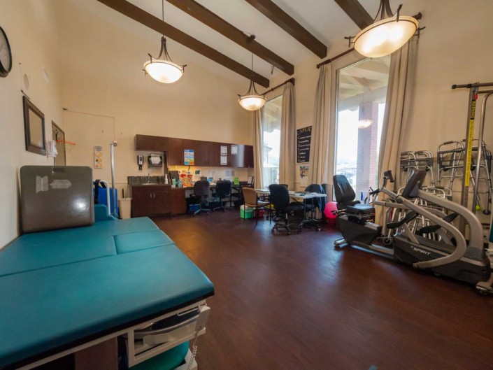 A rehabilitation clinic room equipped with exercise machines and treatment tables.