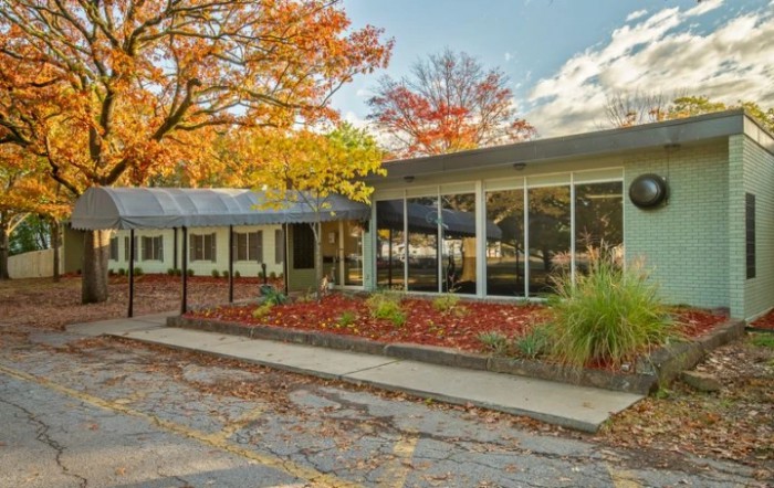 A modern building surrounded by autumn foliage under a cloudy sky.