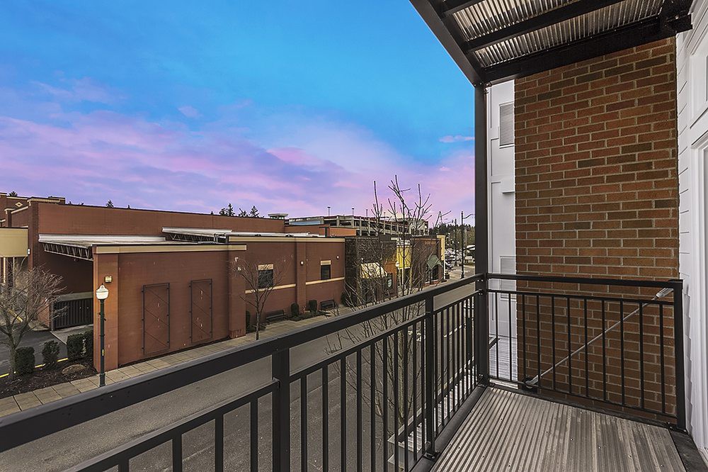 A view from a balcony overlooking the city at sunset, showcasing urban architecture and vibrant skies.